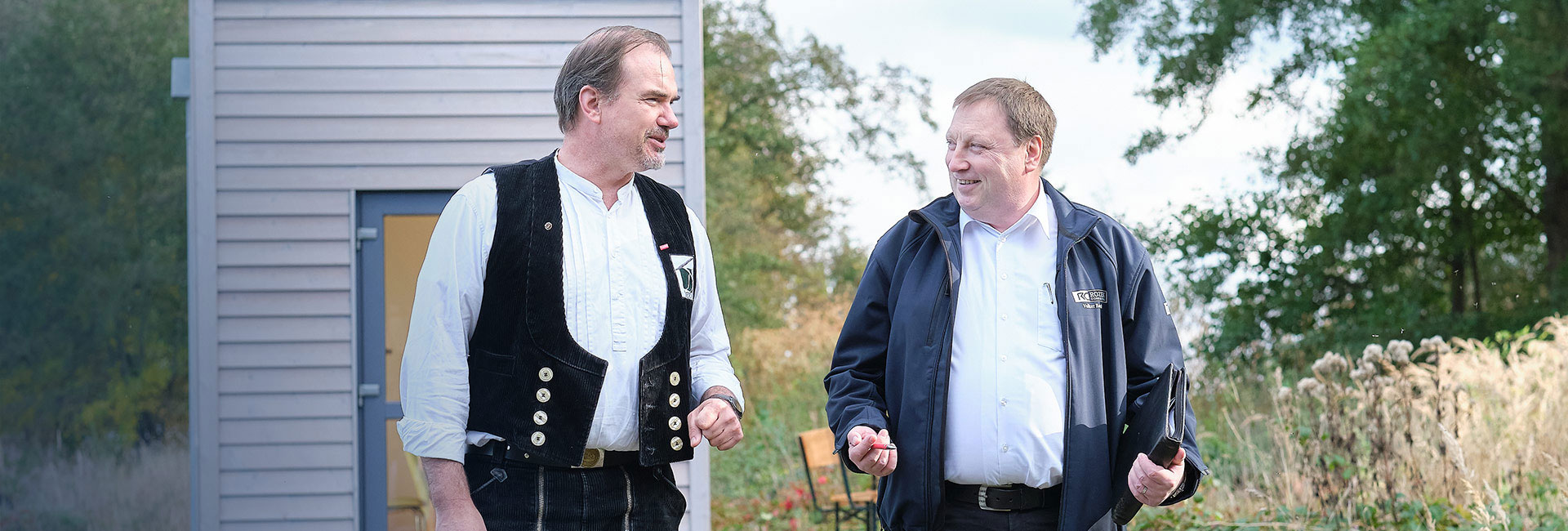 Volker Rozek berät seinen Kunden vor der Produktionshalle über geplante Verbesserungsmaßnahmen und deren effiziente Umsetzung.